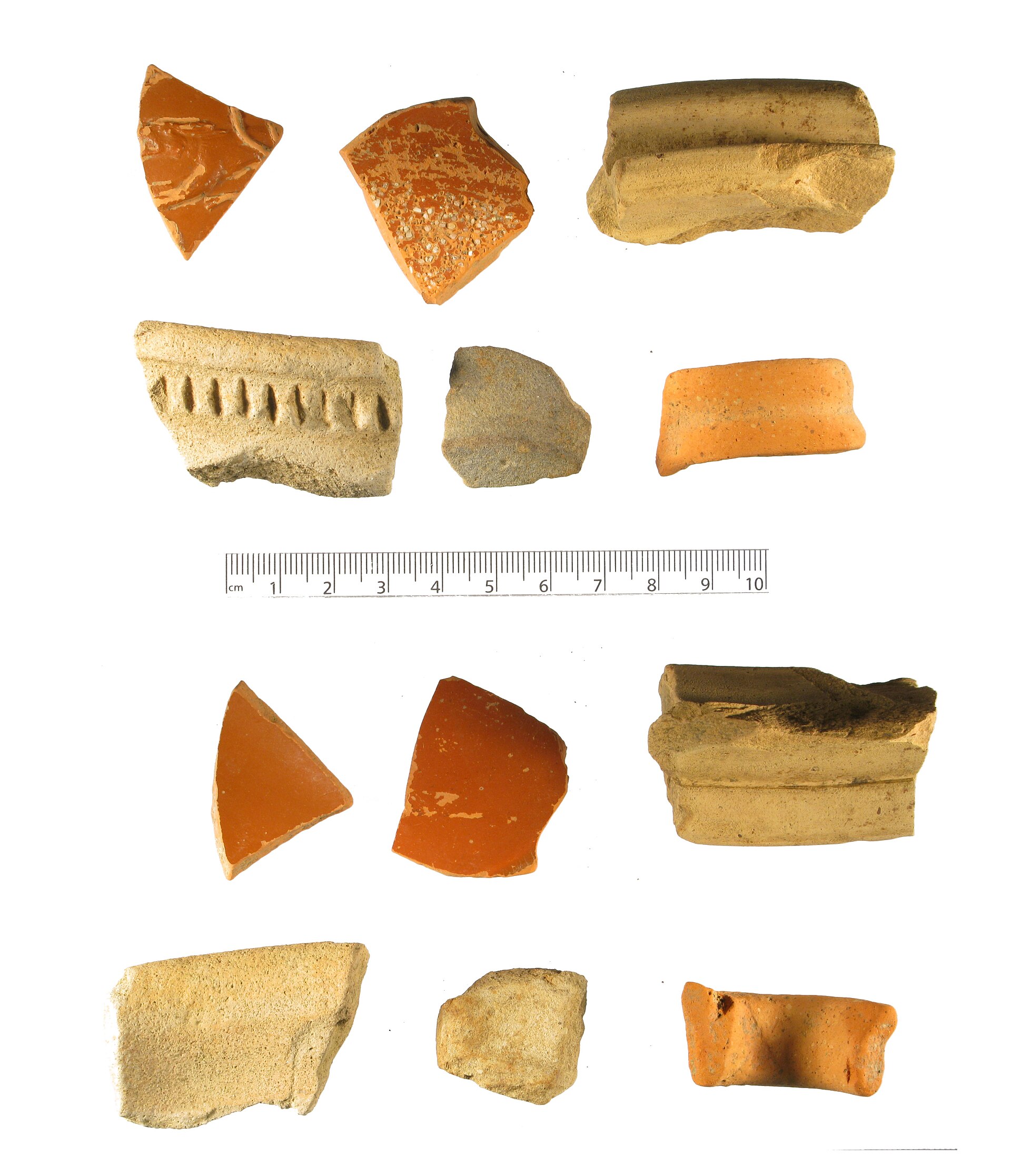 A group of Roman pottery sherds arranged beside a centimetre scale